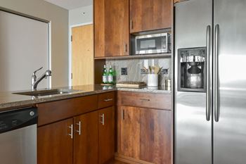 A kitchen with wooden cabinets and a stainless steel refrigerator.